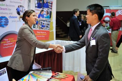 A student shaking hands with a potential employer at the grad fair