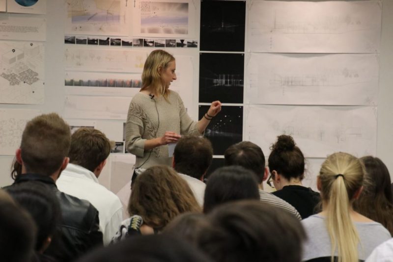 An architecture student presents a project to a room of fellow students.